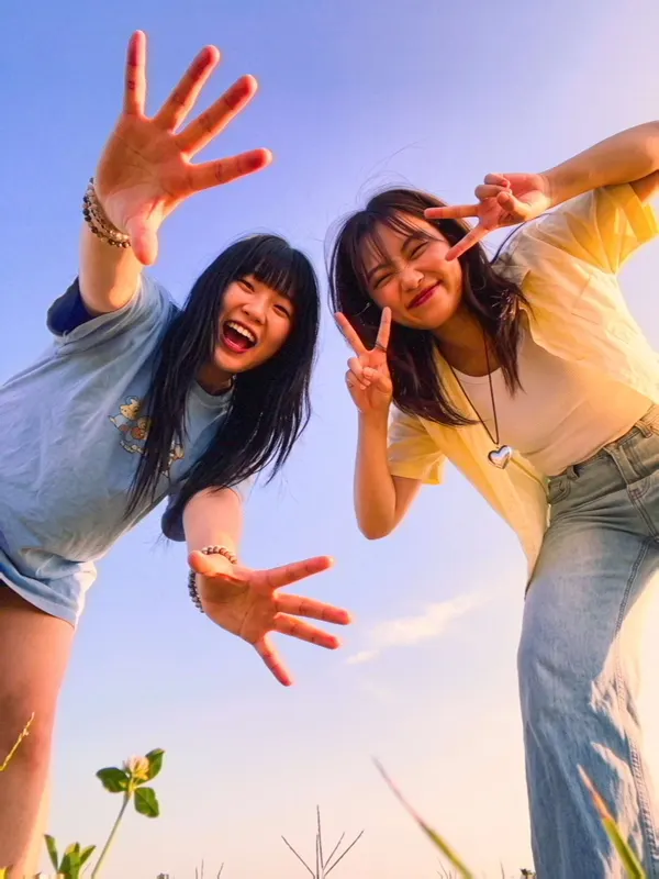 Two friends leaning into the frame against a blue sky.