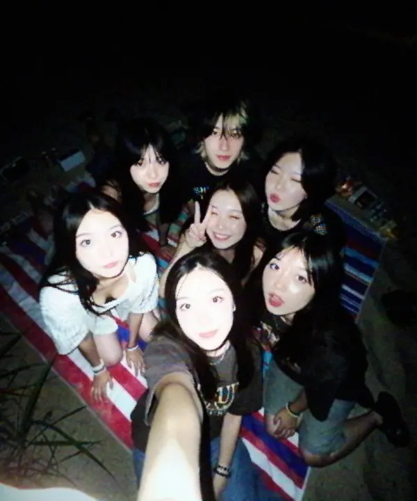 Friends on a picnic blanket at night, small and grainy.
